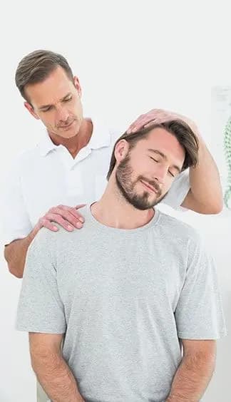 A chiropractor supporting a seated patient during a neck adjustment.