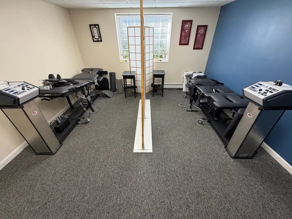 The decompression room at Active Chiropractic in Saco: two black decompression tables, each with its traction unit at the foot, either side of a folding screen, under a window