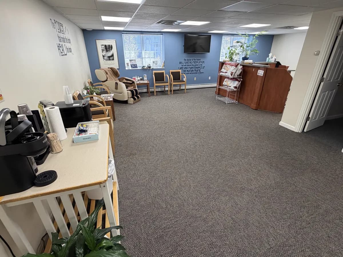 The waiting room at Active Chiropractic in Saco: chairs, a massage chair and the front desk.