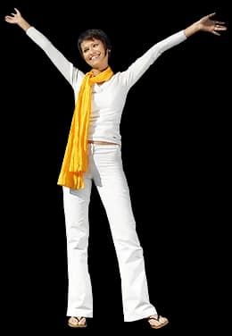 A woman standing outdoors with her arms in the air.