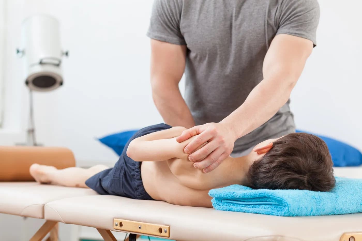 A chiropractor giving a gentle adjustment to a child lying face down on a treatment table